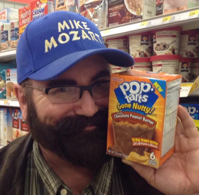 a man holds a cereal box and a blue hat