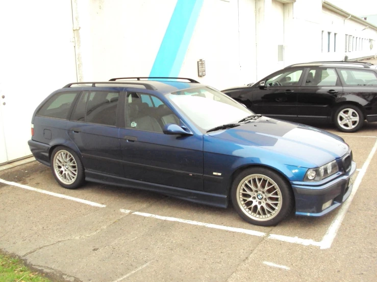 a bmw car parked in a spot between a building