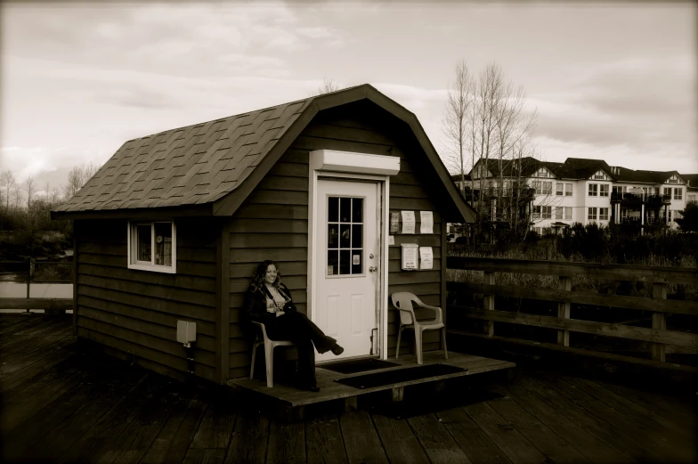 the person is sitting outside the small house