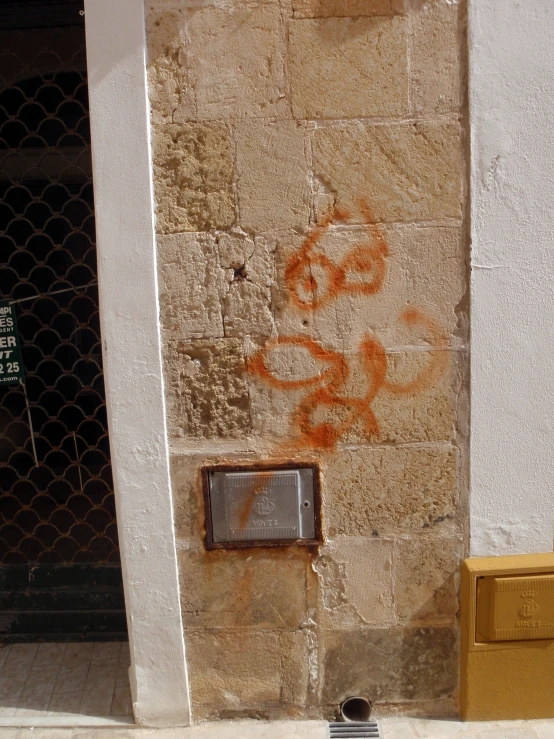 an orange cat is sitting in the sidewalk next to a window