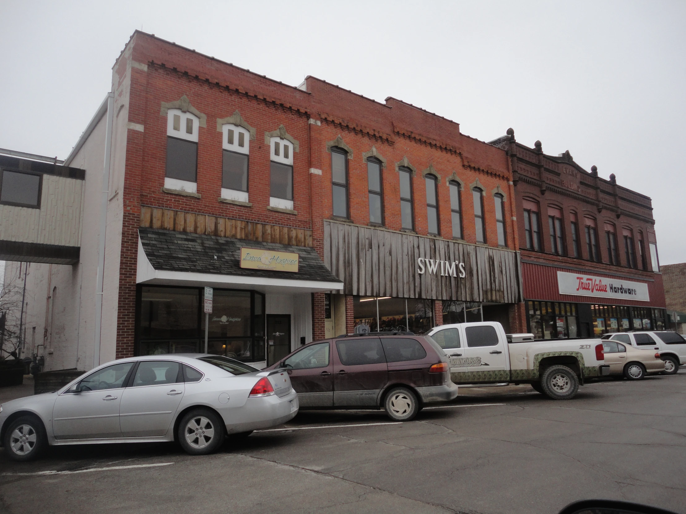 many parked cars are outside of a large brown and white building