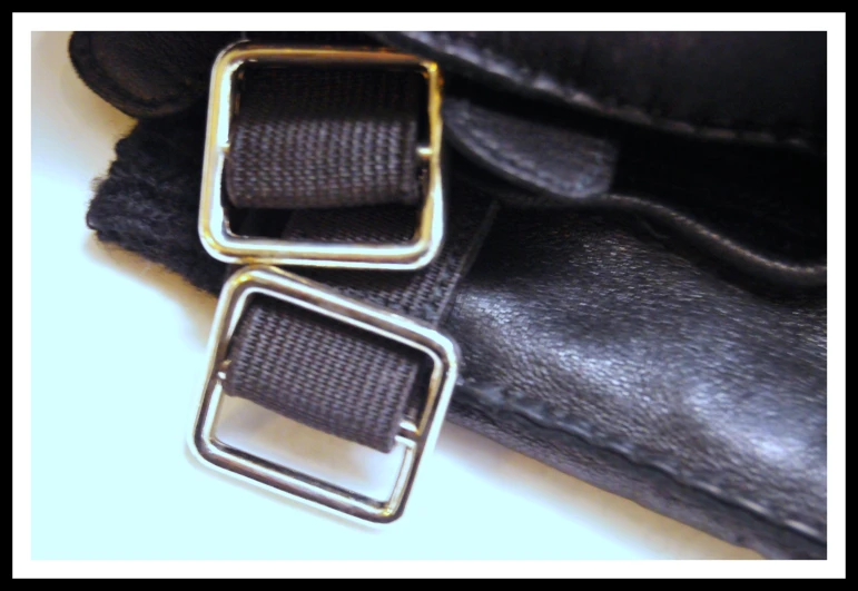 a pair of square silver - toned buckles on black leather