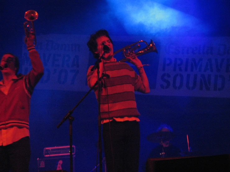 two young men playing instruments on stage at a concert