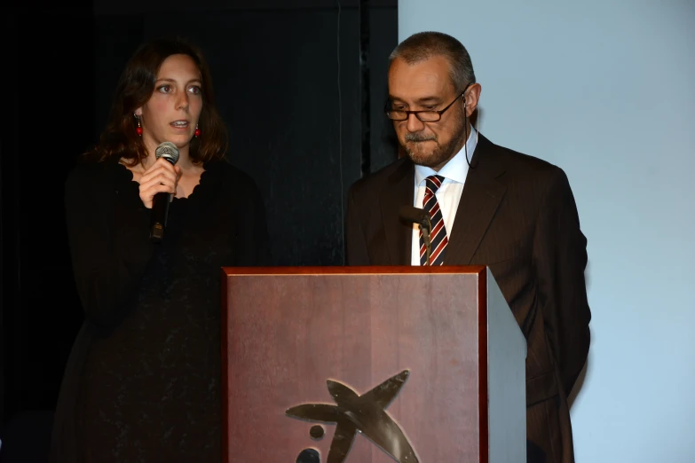 a woman and man standing next to a plaque