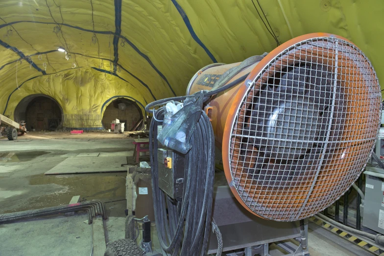 a large fan cooling in a room filled with concrete