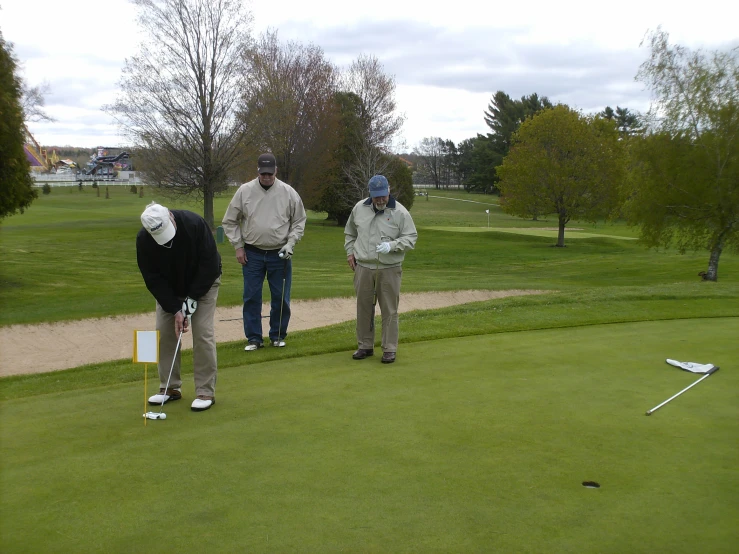 three people in hoodies look at soing while playing golf