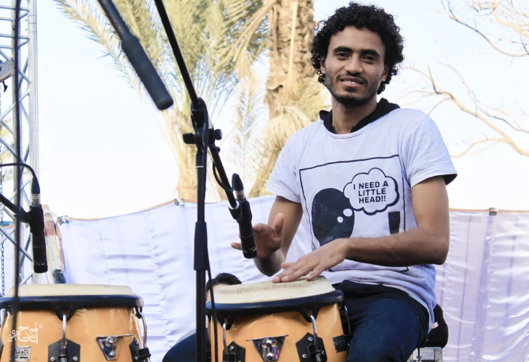 a man is holding his hands out as he sits on a stool while drumming with drum sticks