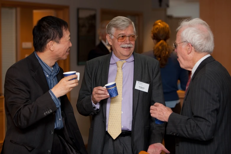 three men in suits having conversation at an event