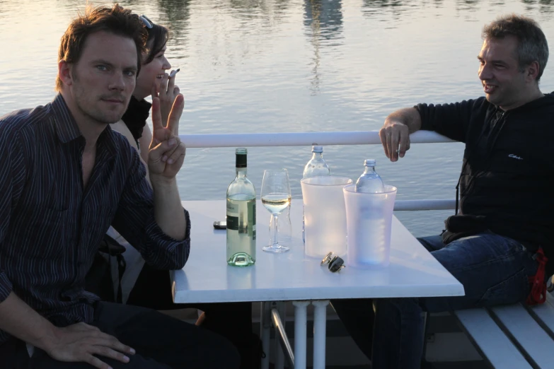 two guys sitting at a table with glasses and bottles of wine