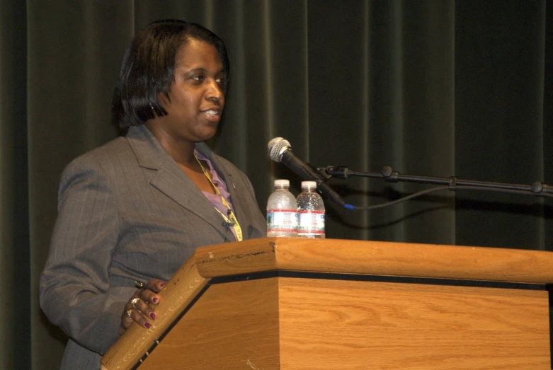 a woman at a podium with her hands in her pockets