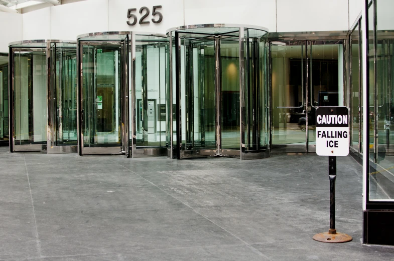 a line of closed glass doors with a sign in the middle