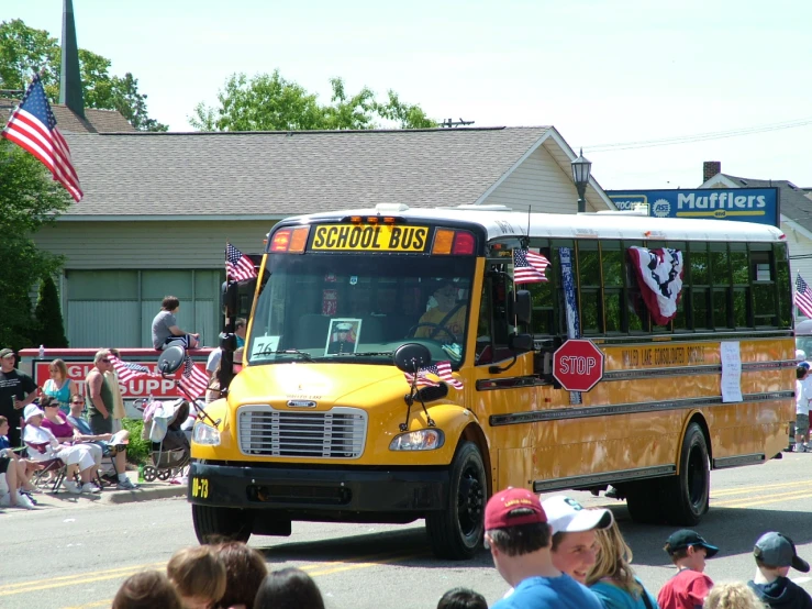 a yellow bus driving past a crowd of people