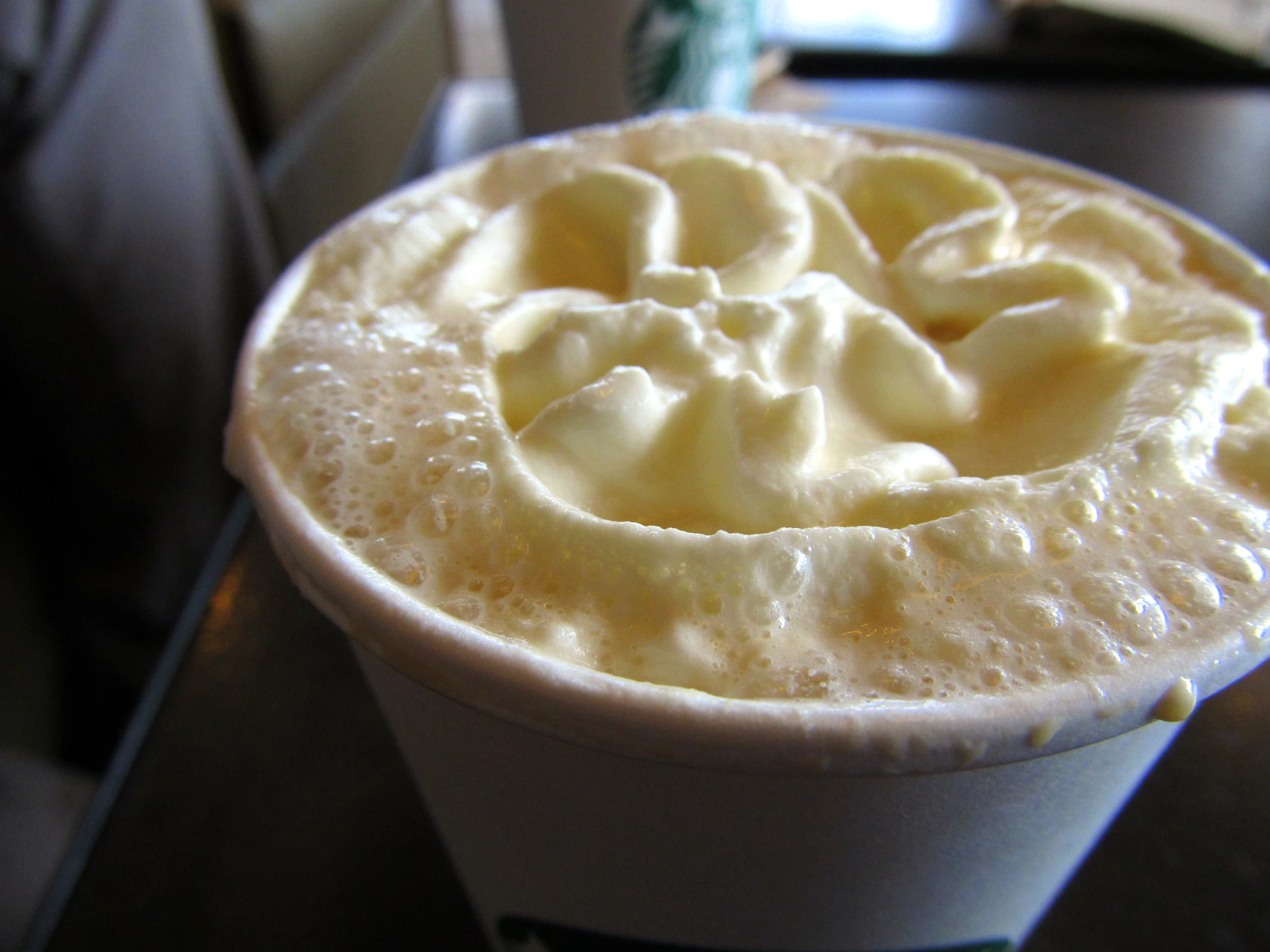 a white drink topped with cream sits on a table