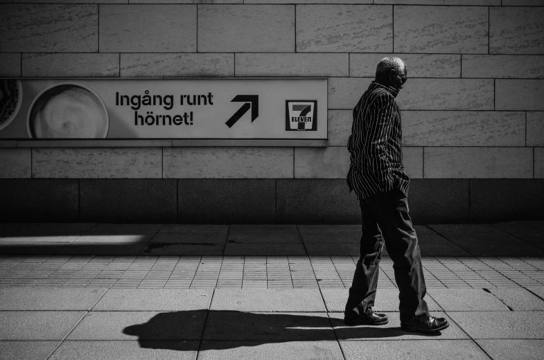 a black and white po of a person walking near a sign