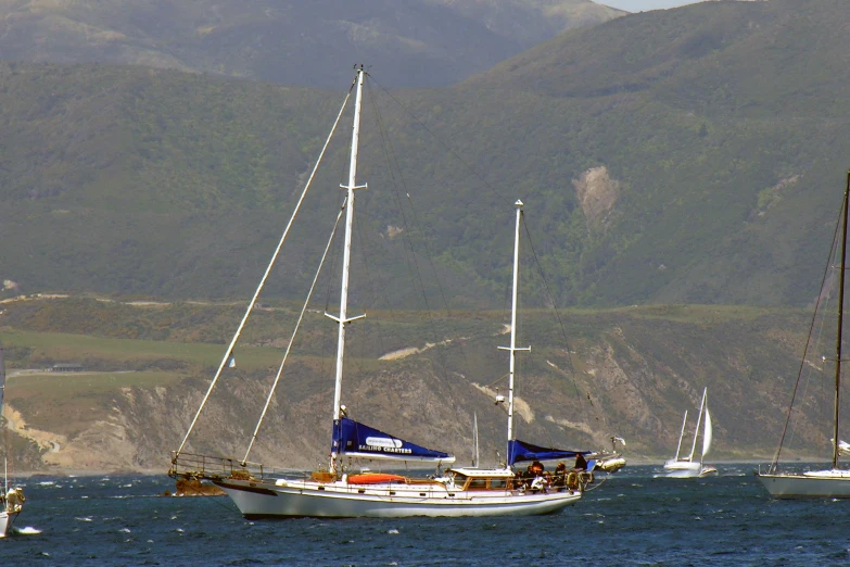 sail boats on the water with mountains behind them