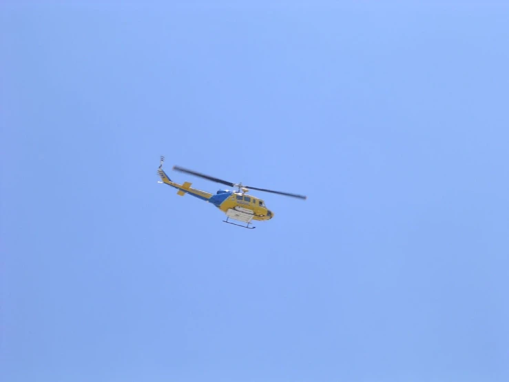 the helicopter is flying high in the clear sky