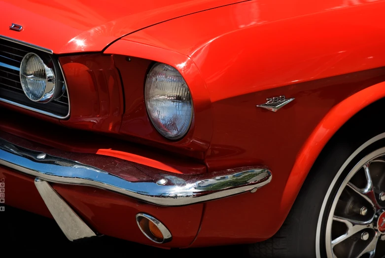the headlight and grille on an old red mustang