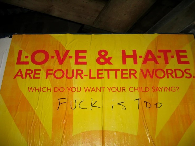 a red and yellow sign in a wood frame with words that read love & hate are four - letter words which do you want your child saying fuk is f, it?
