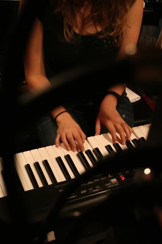 person sitting in front of a keyboard with their hands on the keys