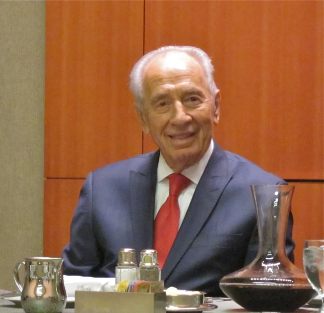 man in a suit at the table smiling and having a conversation