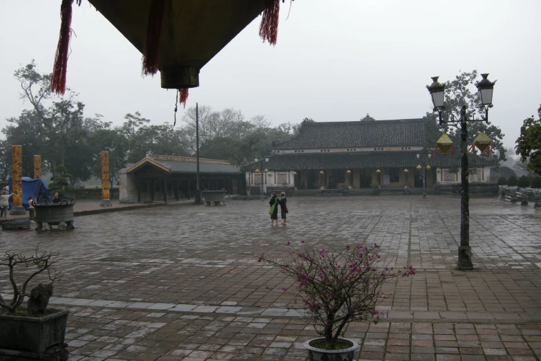 a person standing on a cement sidewalk with an umbrella over