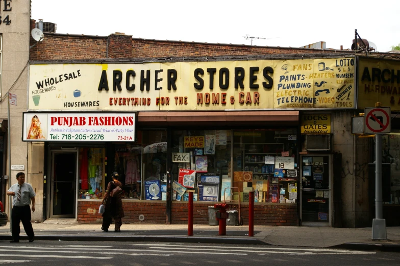 two people walking past a store on the street corner