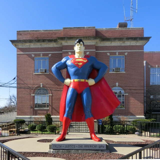 a statue of superman is located in front of a large brick building
