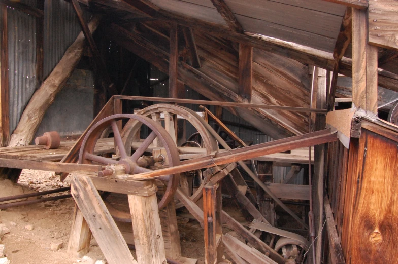 an old wooden building with wooden rails and spoke wheels