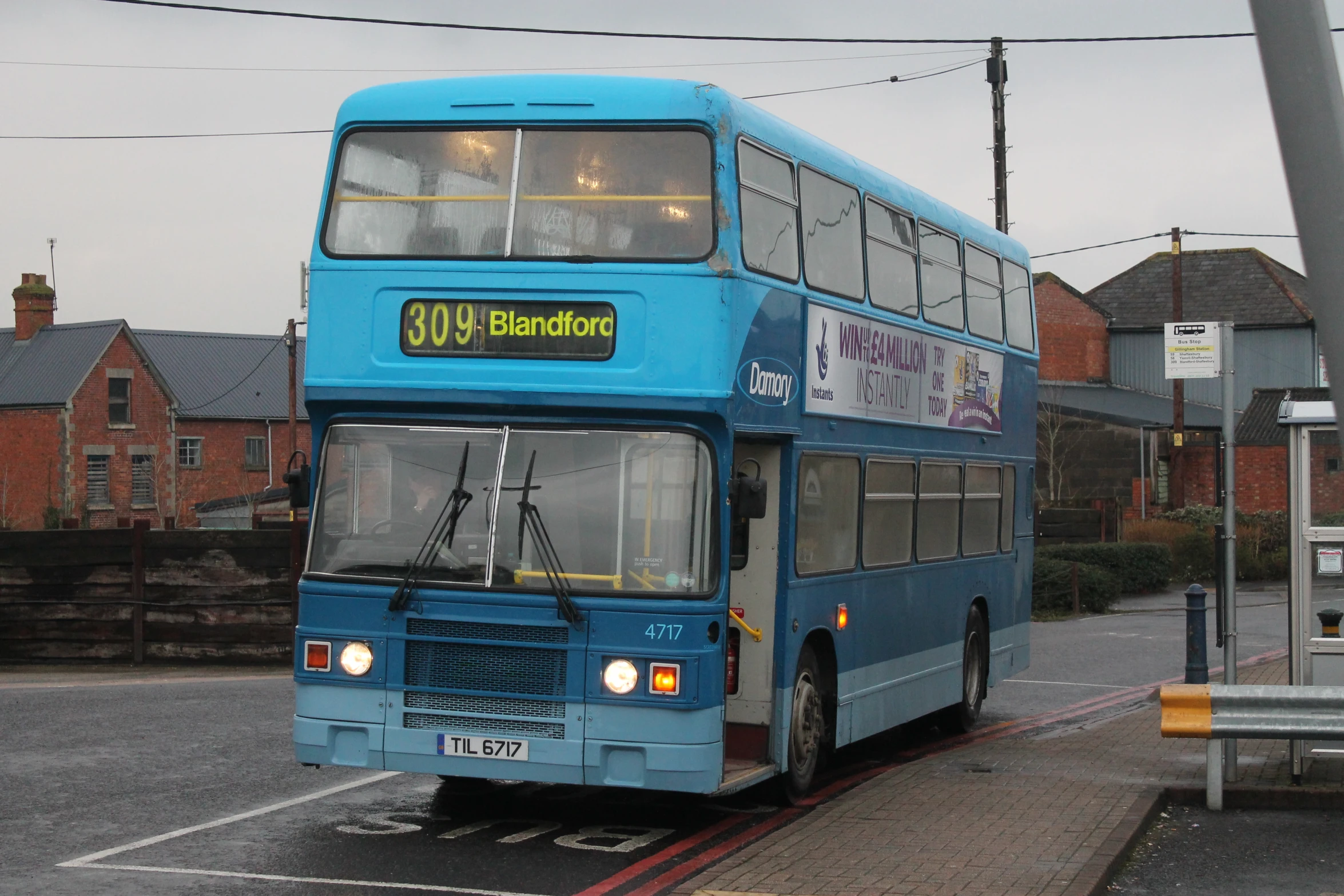 a blue double decker bus driving down the street