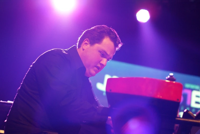 a man sitting down playing piano on stage