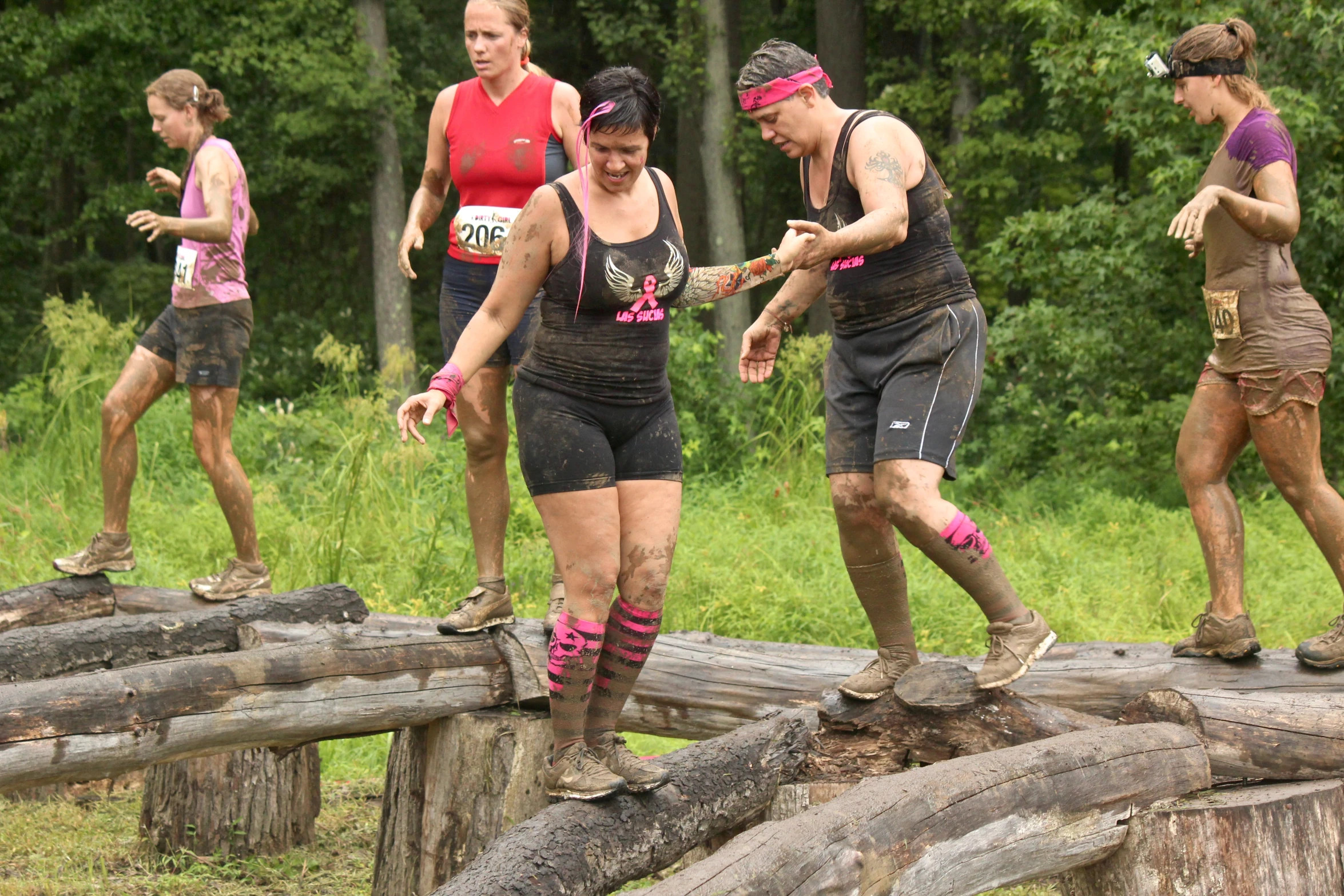 a group of people walking across a wooden log bridge