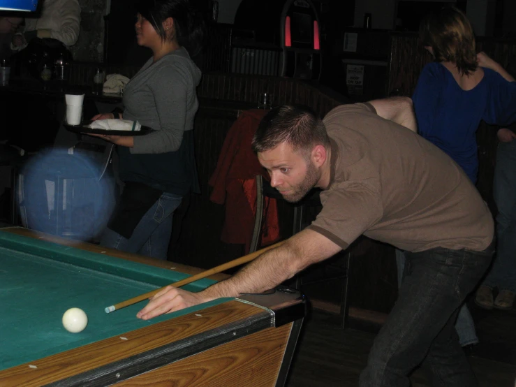 a man leaning over to play billiard in a bar