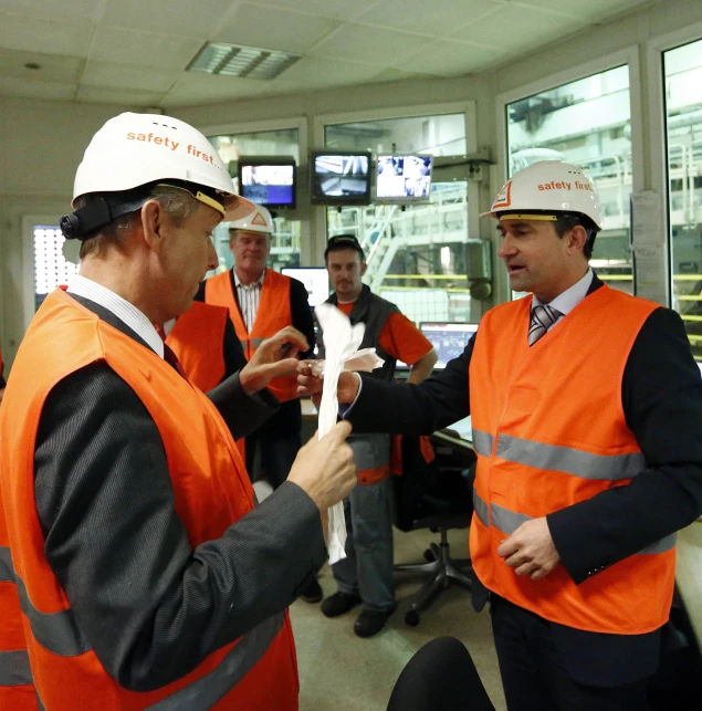 men in orange vests are putting together construction paper