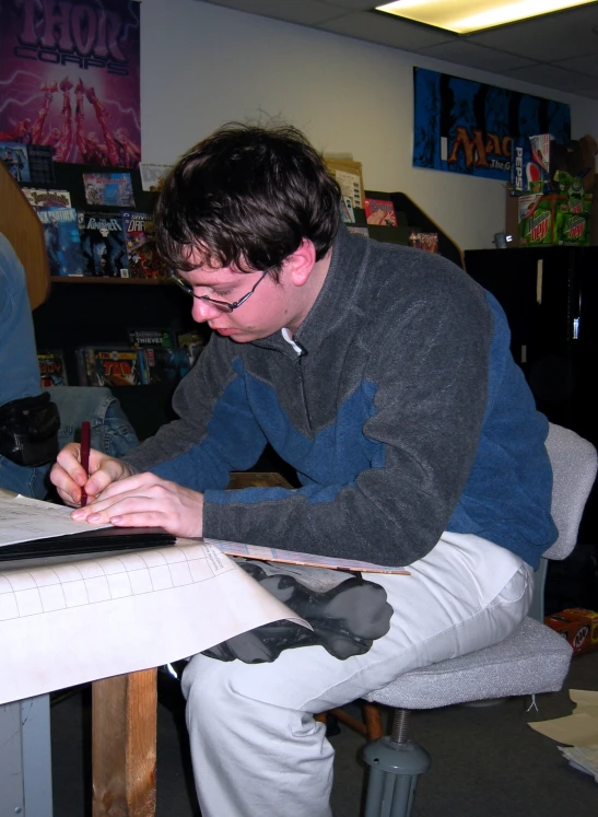 a man in glasses sitting at a table using a laptop