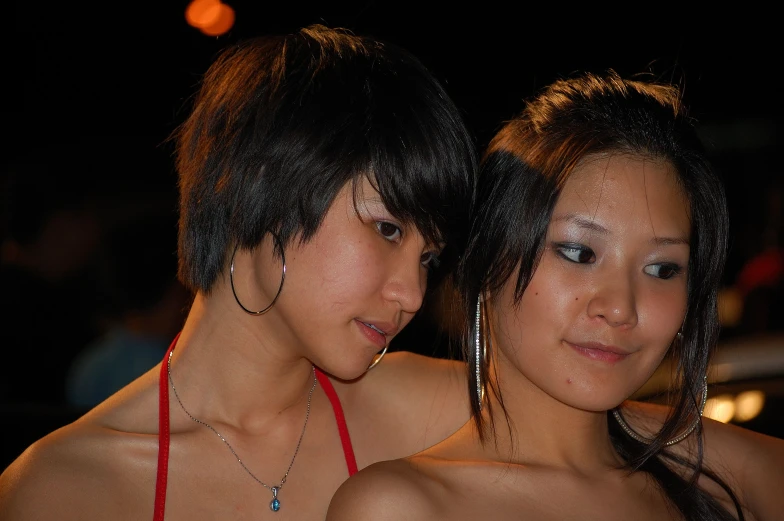 two asian women in short swimsuits standing close together