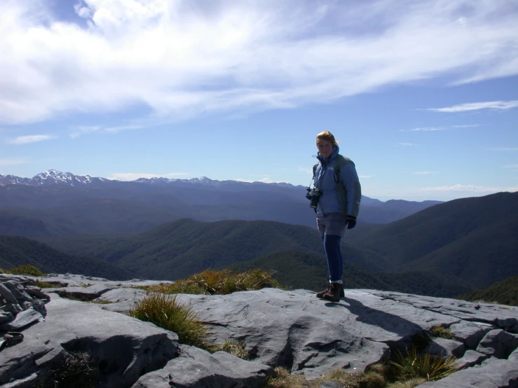 a man standing on top of a rock looking out over a mountain range