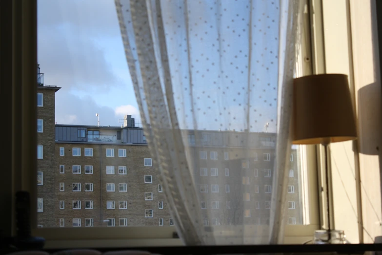 a window with curtained blinds that show the cityscape