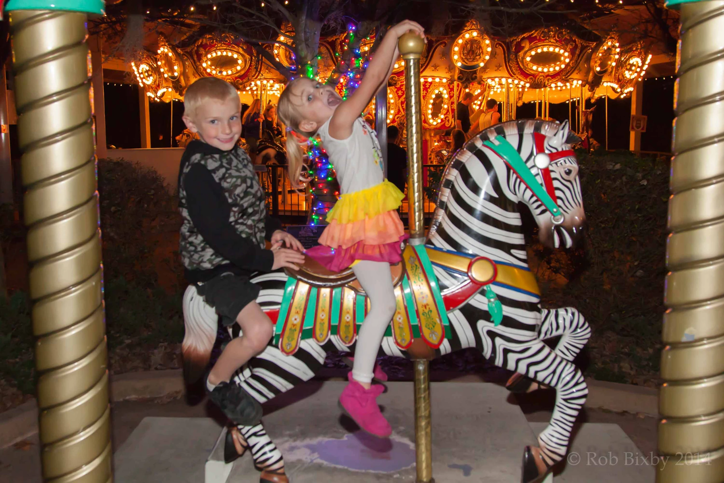 two children on a merry go round at a amut park