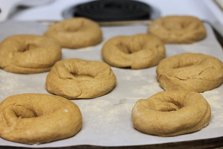 twelve donuts are sitting in an oven, some round and one half, some slightly flat