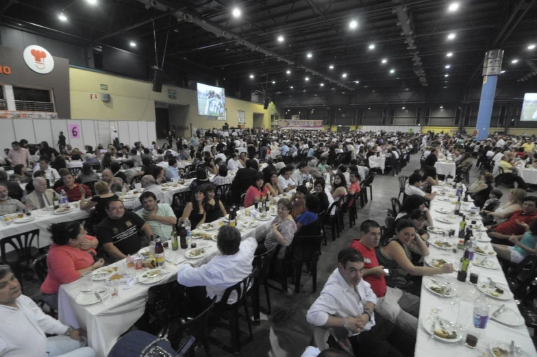 several rows of tables full of people eating dinner