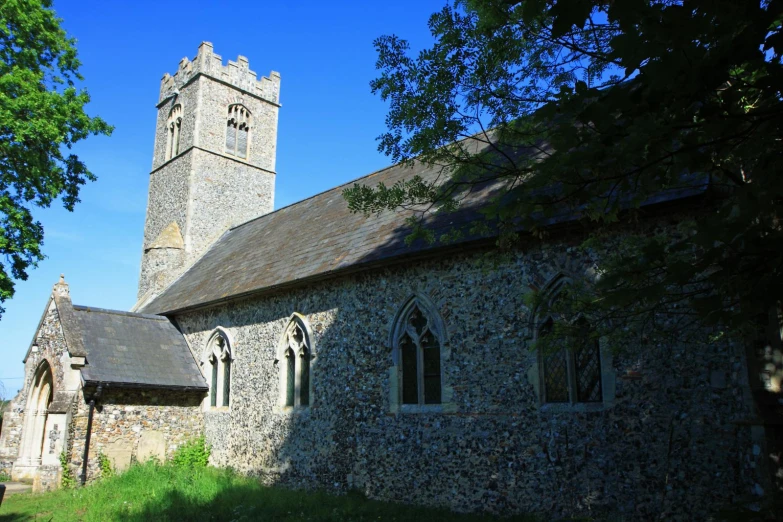 an old church with a steeple surrounded by trees