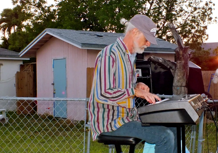 a person sits at a keyboard outside of a pink house