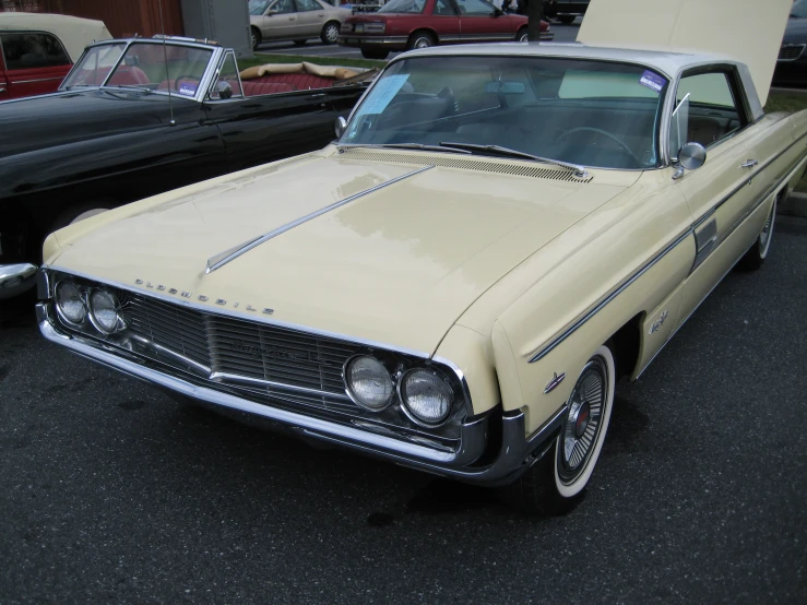 an old yellow car is parked near other classic cars