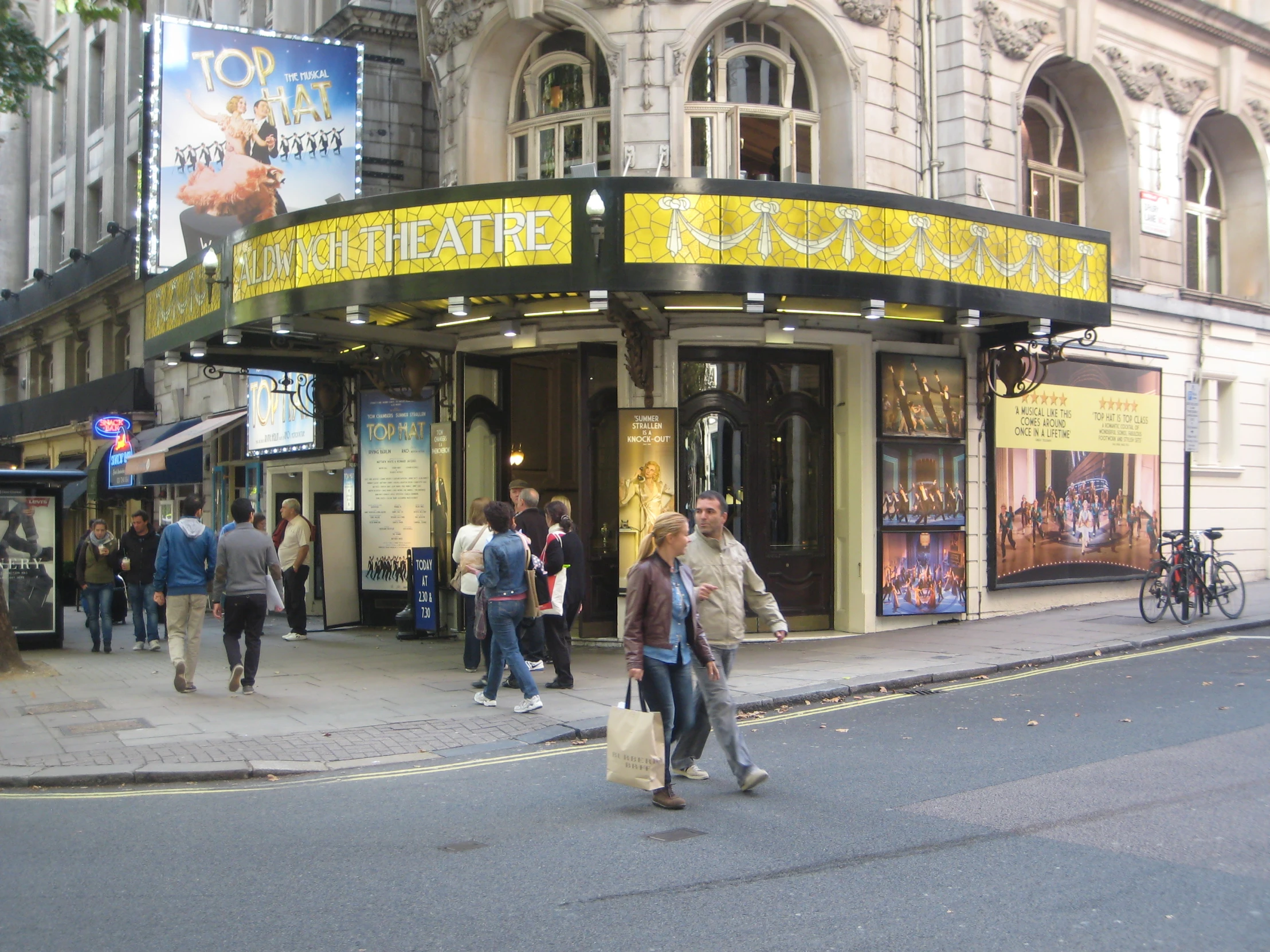 pedestrians walking down the street past a theater