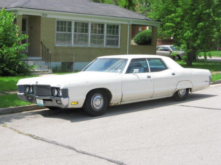 a white car is parked in the street by some houses