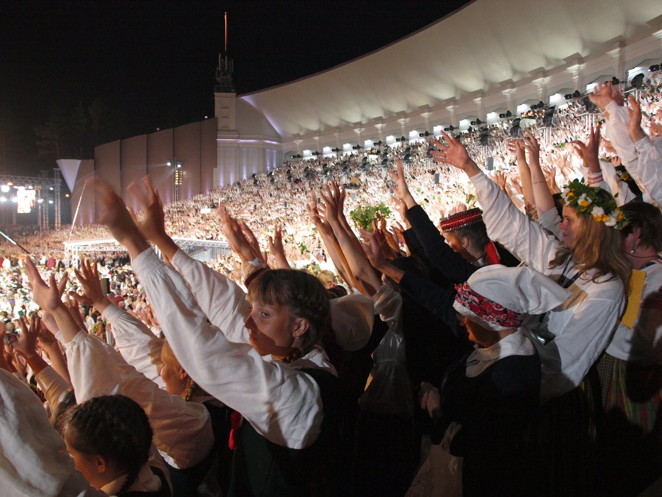 people are standing in a stadium raising their hands