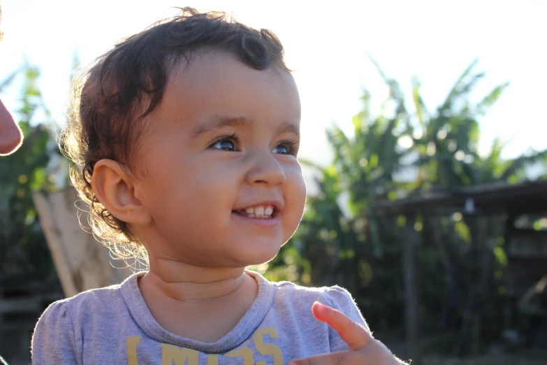 the little child smiles while standing beside someone