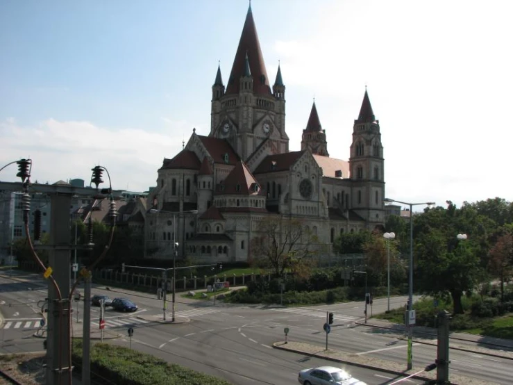 a large building with lots of spires in front of the city street