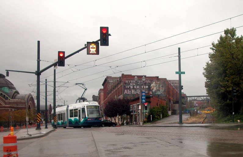 the white commuter train is approaching at the light