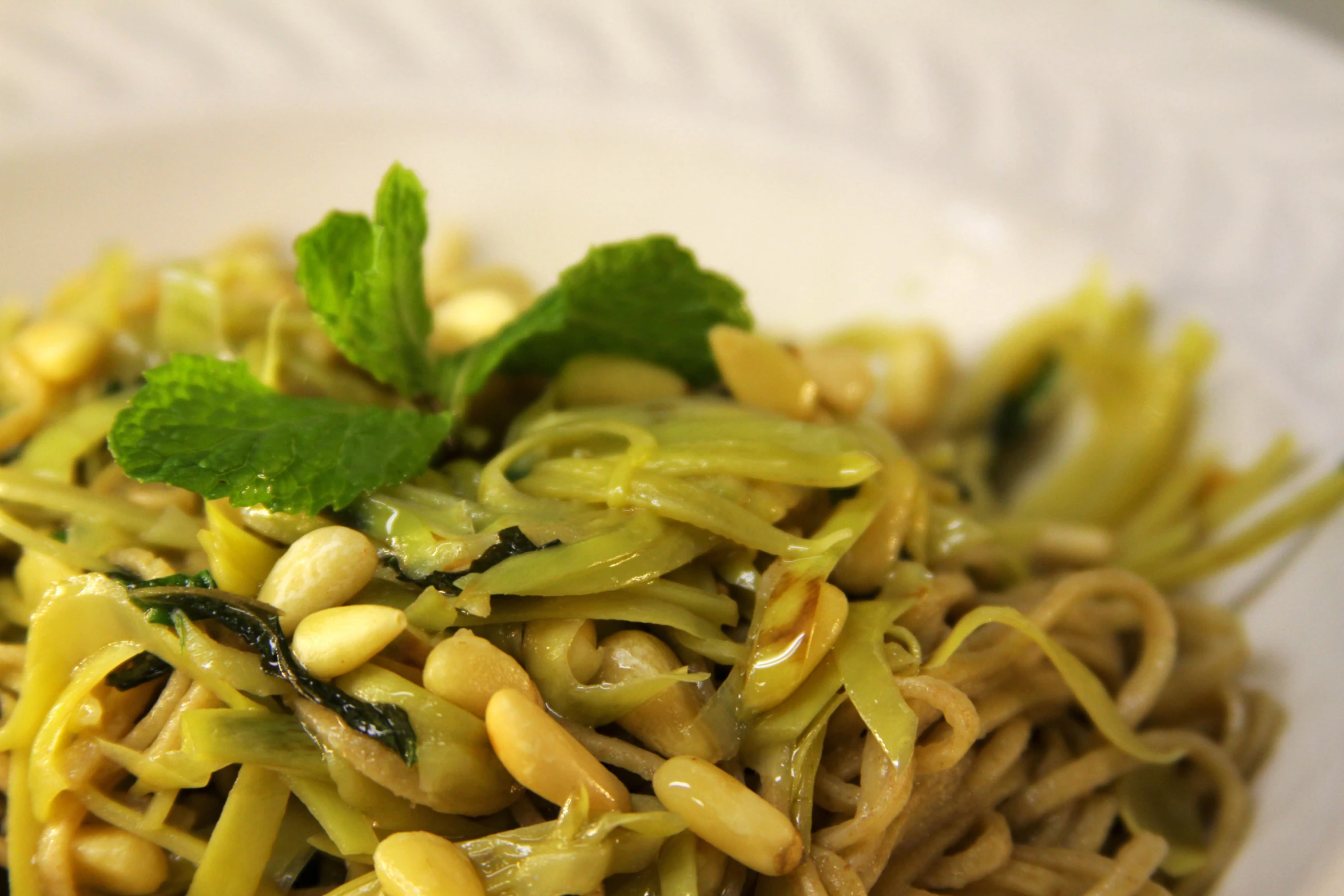 a white bowl topped with noodles and greens